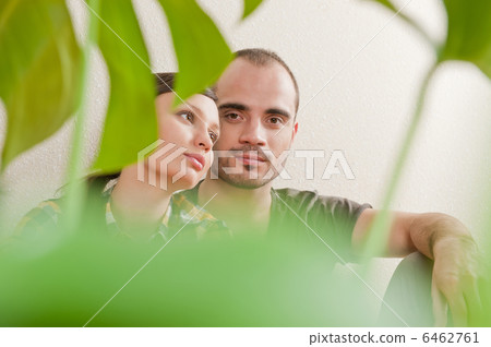 Attractive young adult couple sitting close on hardwood floor in Attractive young adult couple sitting close on hardwood floor in 6462761