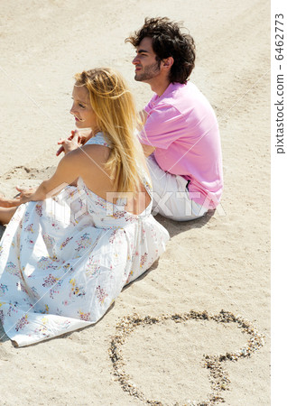 Portrait of young couple sitting together on sand on beach and l Portrait of young couple sitting together on sand on beach and l 6462773