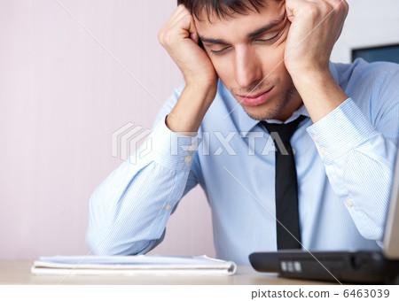 Tired businessman sleeping at his desk in the office with both a Tired businessman sleeping at his desk in the office with both a 6463039