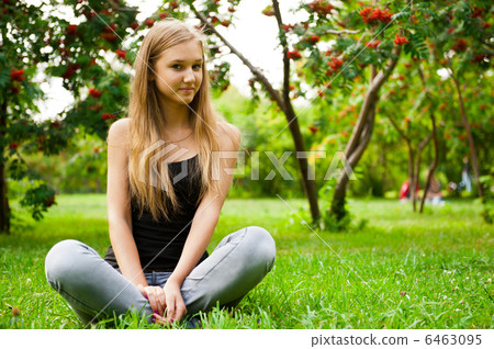 Beautiful female student outdoors sitting on grass at campus par Beautiful female student outdoors sitting on grass at campus par 6463095