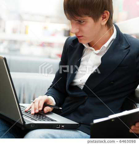 Portrait of handsome young man working with laptop at cafe at bu Portrait of handsome young man working with laptop at cafe at bu 6463098