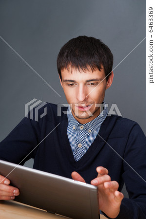 Closeup of a young smiling business man sitting at his office ag 6463369