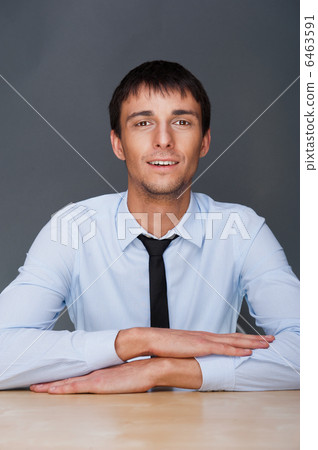 Portrait of young business man on a desk. He is sitting at his n Portrait of young business man on a desk. He is sitting at his n 6463591