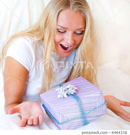 Bedroom surprise present - young happy woman in bedroom 6464138