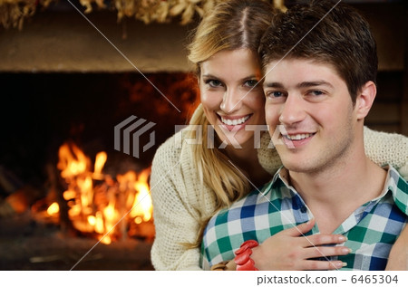 Young romantic couple sitting on sofa in front of fireplace at h Young romantic couple sitting on sofa in front of fireplace at h 6465304