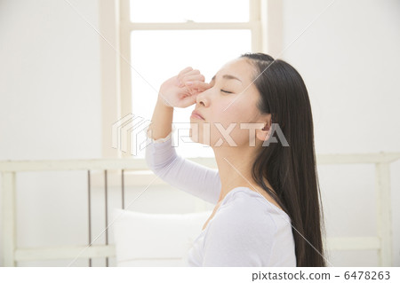 A young woman waking up in bed 6478263