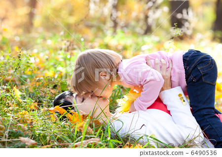 beautiful young mother and her daughter lying on the autumn leav beautiful young mother and her daughter lying on the autumn leav 6490536