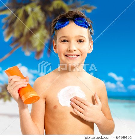 boy applying sun block cream on the tanned body 6499495