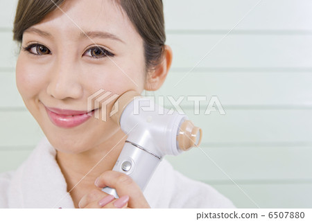 A woman using a facial instrument 6507880
