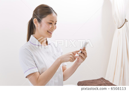 A lady in a white suit operating a smartphone A lady in a white suit operating a smartphone 6508113