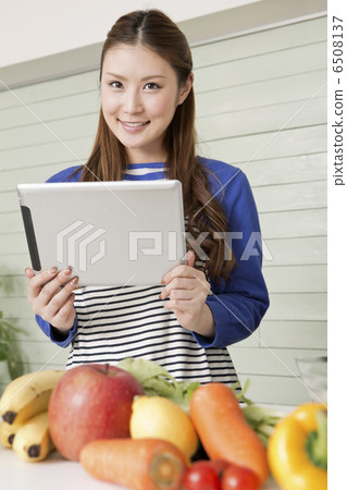 A woman who operates a tablet terminal in the kitchen A woman who operates a tablet terminal in the kitchen 6508137