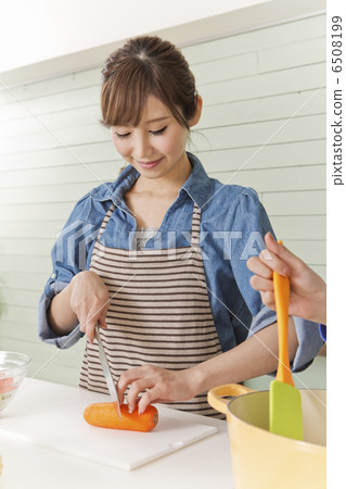 A woman cutting carrots with a kitchen knife A woman cutting carrots with a kitchen knife 6508199