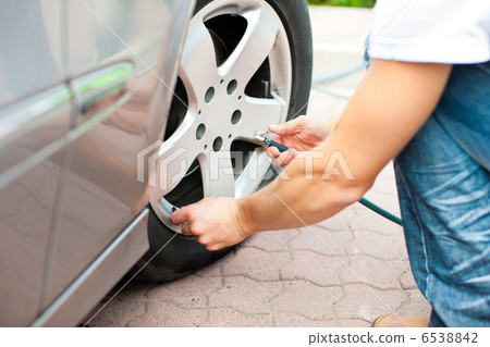 Man is controlling the tire pressure of his car 6538842