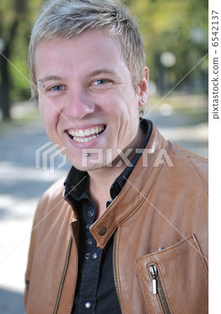 Handsome young man smiling outdoors 6542137