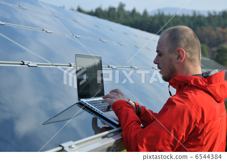 engineer using laptop at solar panels plant field 6544384