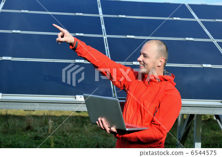 engineer using laptop at solar panels plant field 6544575