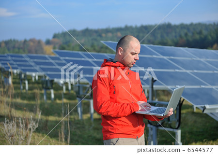 engineer using laptop at solar panels plant field 6544577