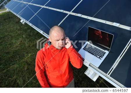 engineer using laptop at solar panels plant field 6544597