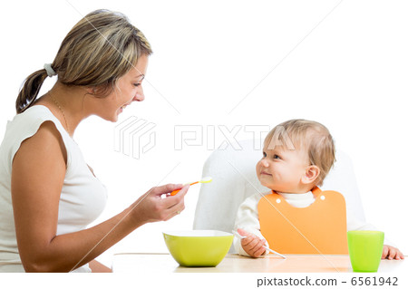 mother spoon-feeding her baby girl mother spoon-feeding her baby girl 6561942