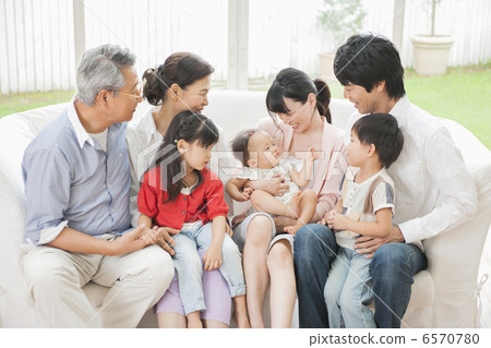 Three generations family sitting on the sofa in the living room 6570780