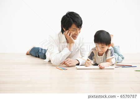 A boy painting with his father in the living room 6570787