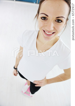 happy diet concept with young woman on pink scale 6572917