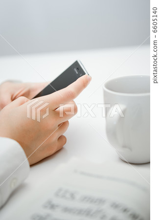 A businesswoman's hands operating a smartphone and a coffee cup. A businesswoman's hands operating a smartphone and a coffee cup. 6605140
