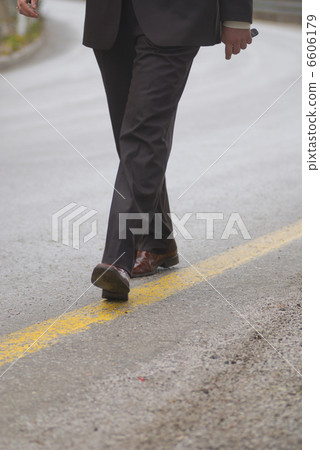 .businessman walking on yellow line .businessman walking on yellow line 6606179