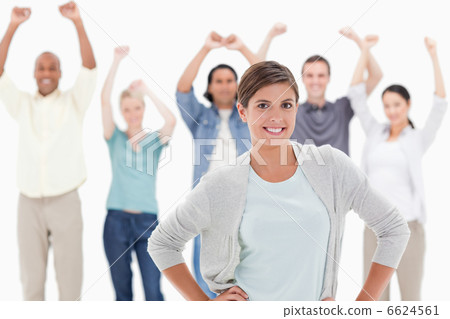 Woman with her hands on hips with people behind raising their ar 6624561