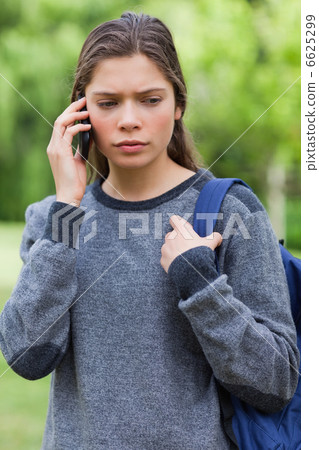 Serious student looking down while talking on the phone 6625299