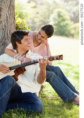 Woman looking at her friend while holding him as her plays the g Woman looking at her friend while holding him as her plays the g 6627520