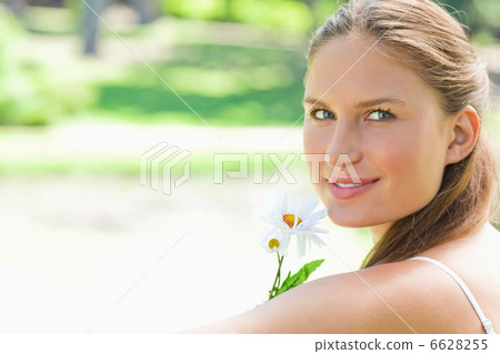 Side view of woman with a flower in the park Side view of woman with a flower in the park 6628255