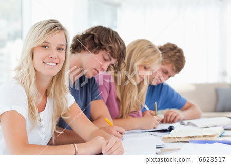 Students working as one girl smiles and looks at the camera Students working as one girl smiles and looks at the camera 6628517
