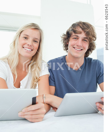 A couple with tablets smile and look at the camera A couple with tablets smile and look at the camera 6628543