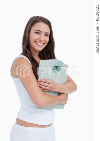 smiling young woman holding a weighing scales smiling young woman holding a weighing scales 6628625