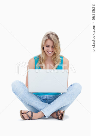 A woman is sitting on the ground looking at her laptop A woman is sitting on the ground looking at her laptop 6628628