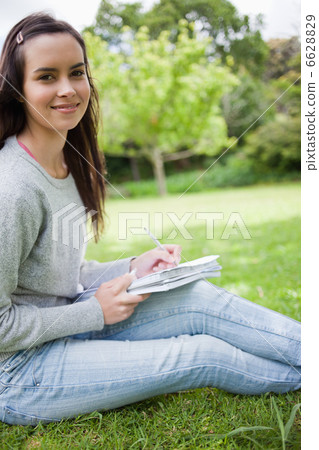Young smiling girl sitting in the countryside while doing her ho Young smiling girl sitting in the countryside while doing her ho 6628829