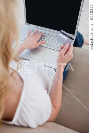 Overhead view of a woman holding a bank card and typing on a lap Overhead view of a woman holding a bank card and typing on a lap 6628832