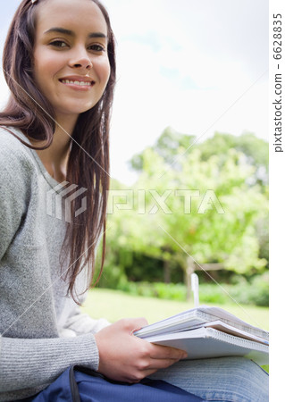 Young smiling girl looking at the camera while doing her homewor Young smiling girl looking at the camera while doing her homewor 6628835