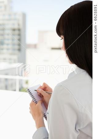 A woman with her back turned begins to write down some informati A woman with her back turned begins to write down some informati 6628891