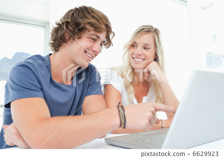 A smiling couple looking at the laptop with the woman looking at 6629923