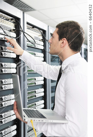 businessman with laptop in network server room businessman with laptop in network server room 6640432