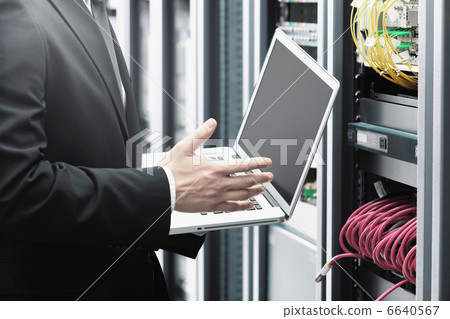 businessman with laptop in network server room businessman with laptop in network server room 6640567