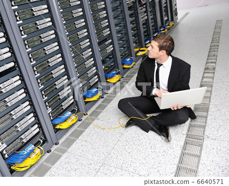 businessman with laptop in network server room 6640571