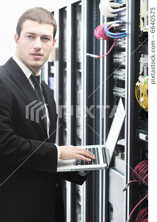 businessman with laptop in network server room businessman with laptop in network server room 6640575