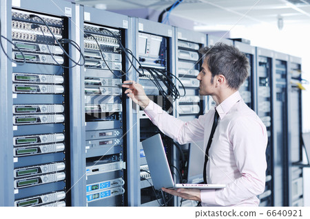 businessman with laptop in network server room 6640921