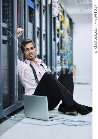 businessman with laptop in network server room 6641017