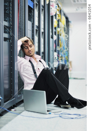 businessman with laptop in network server room 6641054