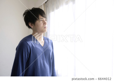 A young twilight man at the window side 6644012