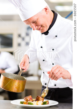 Chef in restaurant kitchen preparing food 6665507